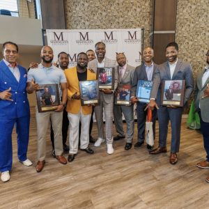 Group of men posing in front of branded backdrop
